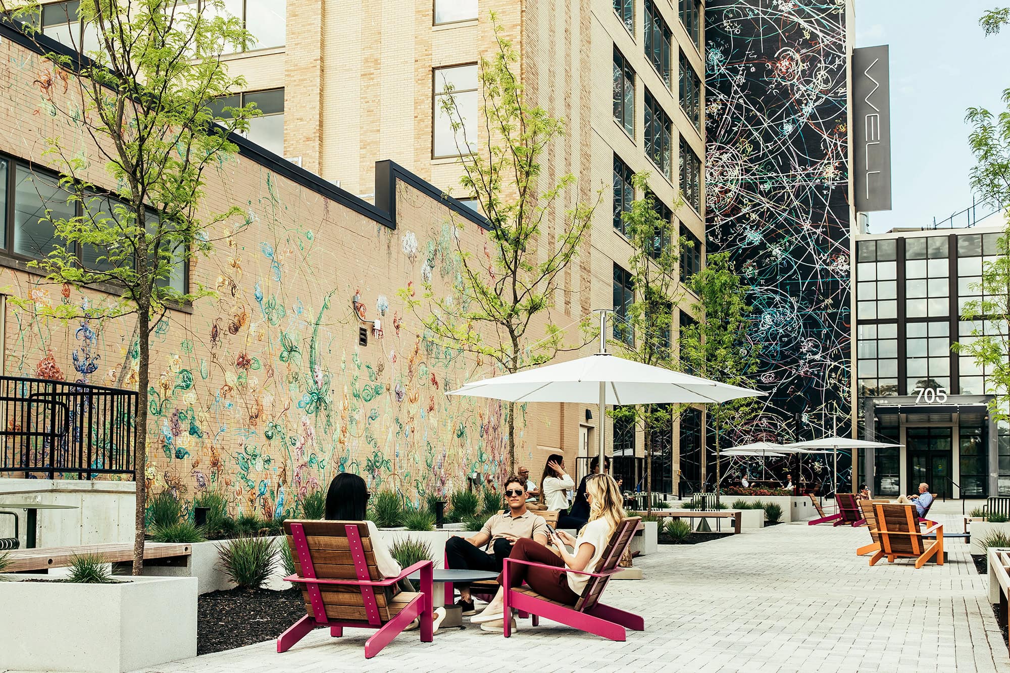 Outdoor seating area at The Grove with colorful mural and umbrellas for shade
