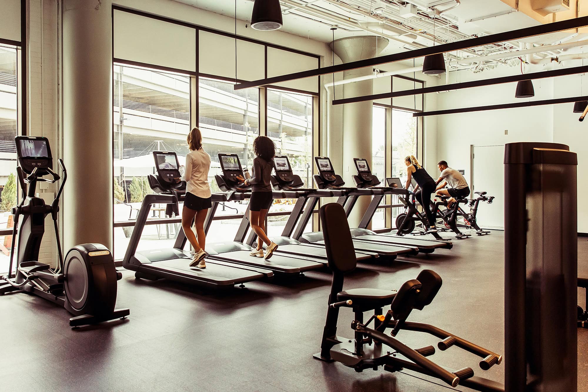People exercising on treadmills and bikes in a modern fitness center