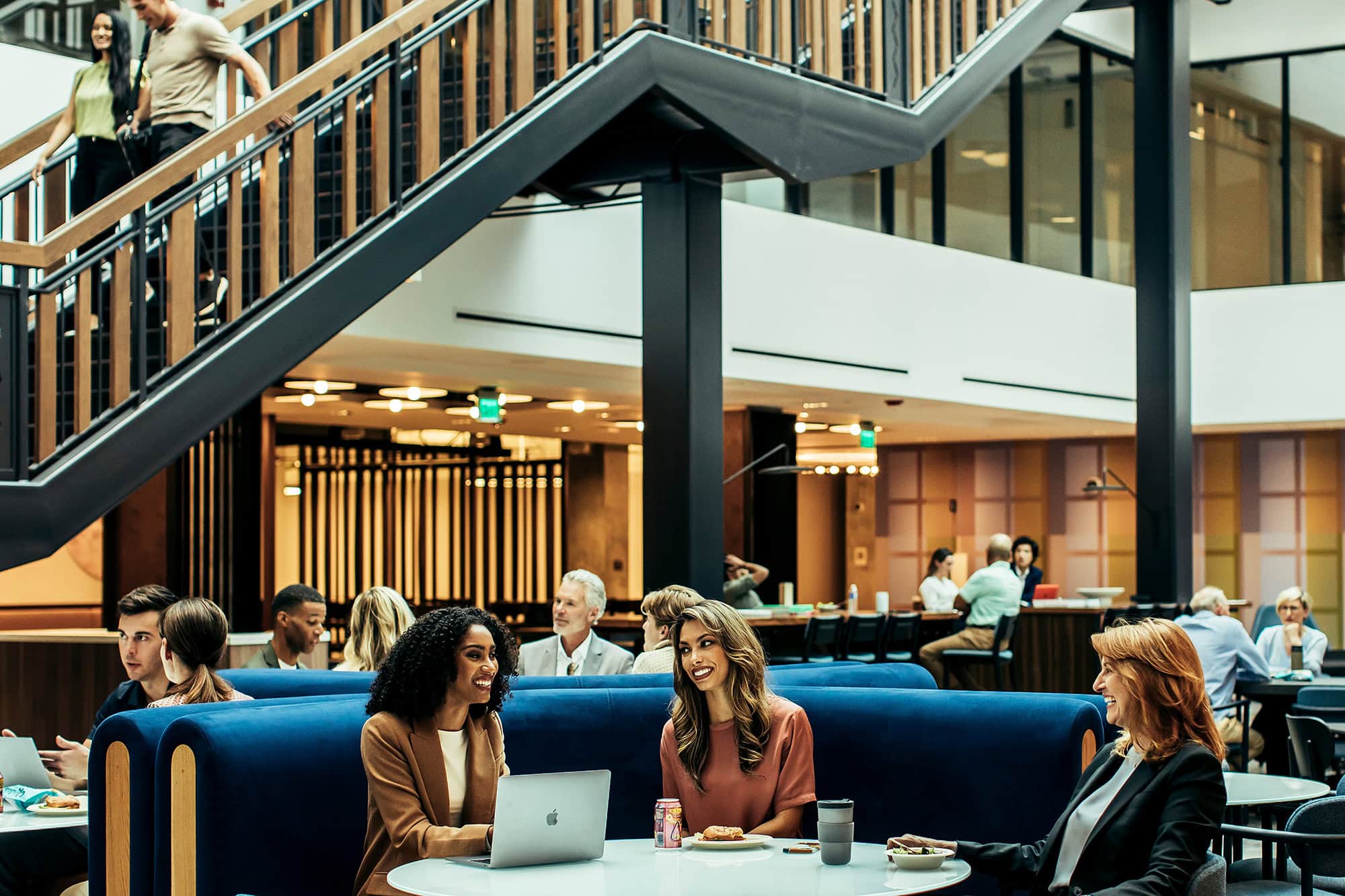 Modern atrium with professionals engaging in conversation and working on laptops
