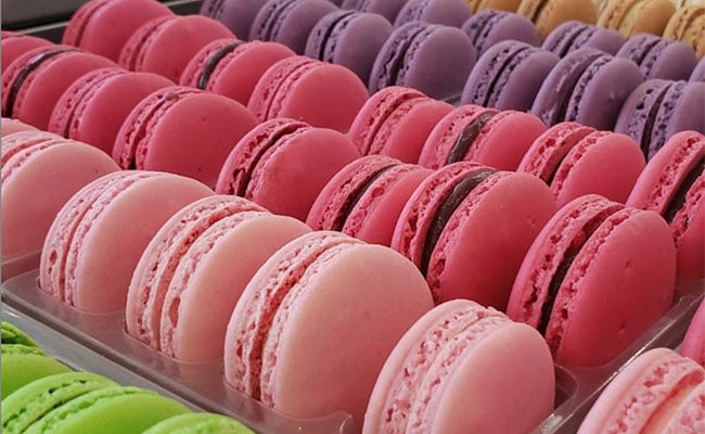 Colorful macarons arranged in rows at Praliné bakery, featuring pink, purple, and other varieties.